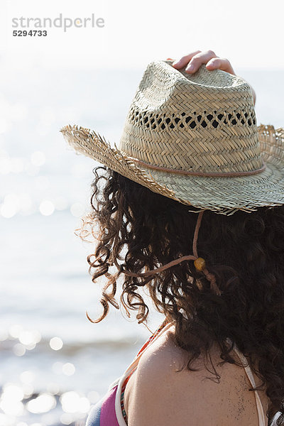 Frau mit Sonnenhut am Strand