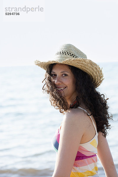 Lächelnde Frau mit Sonnenhut am Strand
