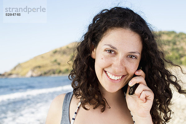 Frau beim Telefonieren am Strand