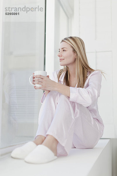 Frau bei einer Tasse Kaffee im Schlafanzug