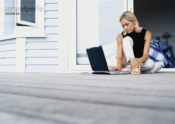 Frau mit Laptop auf der Veranda