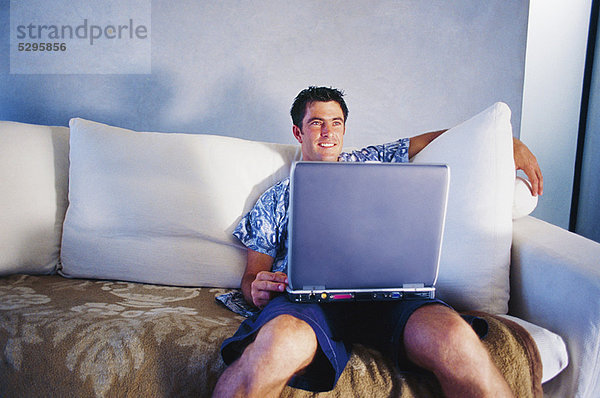 Mann mit Laptop auf der Couch