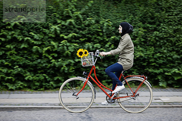 Frau im Kopftuch Radfahren auf dem Handy