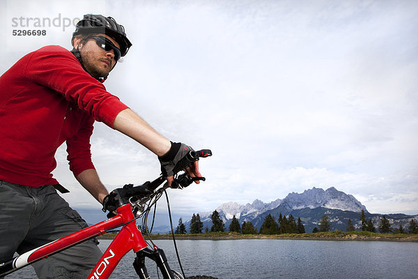 Mann mit Mountainbike an einem See