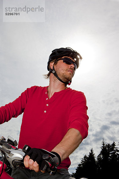 Mann in rotem Shirt auf einem Mountainbike