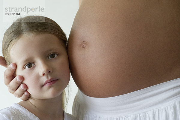 Mädchen hört auf Mutters schwangeren Bauch