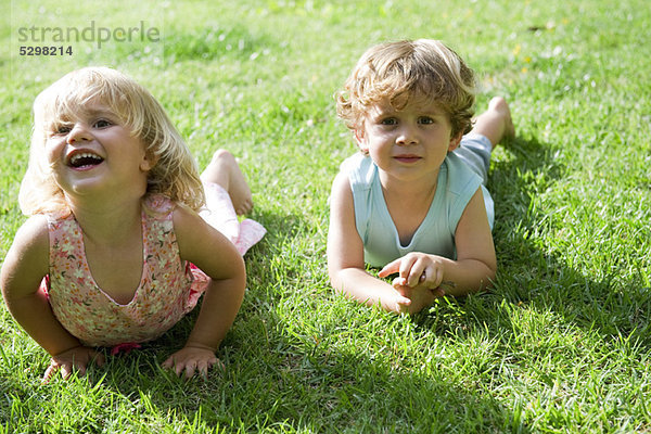 Junge Geschwister auf Gras liegend