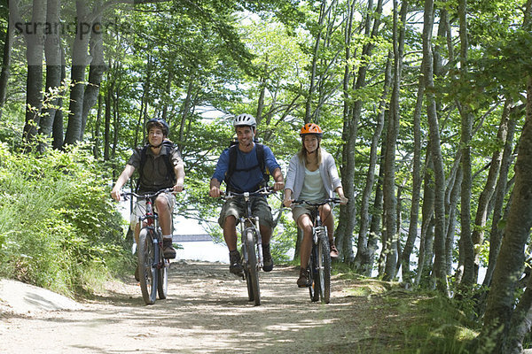 Freunde  die mit dem Fahrrad durch den Wald fahren.