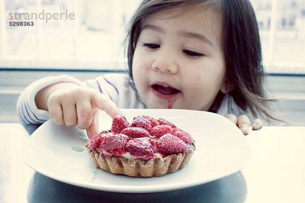 Kleines Mädchen bekommt Geschmack von Himbeertorte