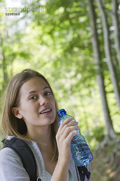 Frau hält abgefülltes Wasser im Wald.