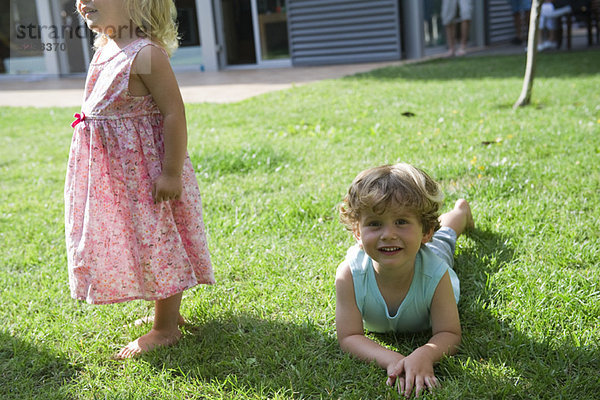 Junge spielt mit seiner Schwester auf dem Rasen