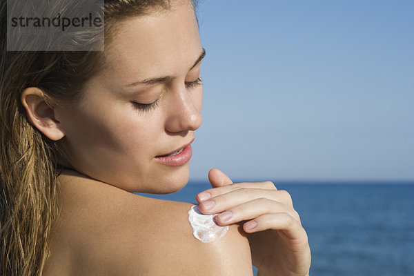 Frau mit Sonnencreme am Strand