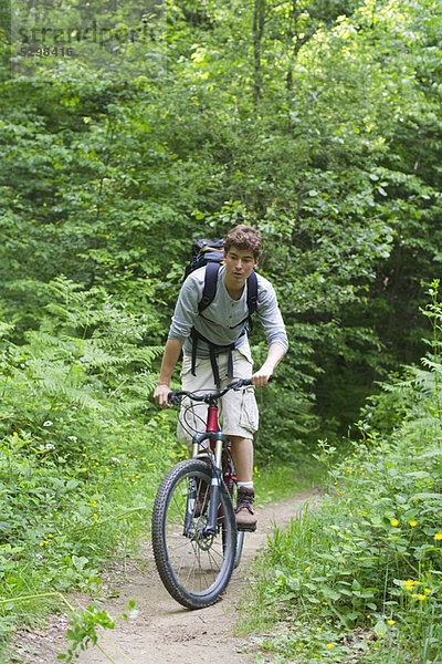Mann fährt mit dem Fahrrad durch den Wald