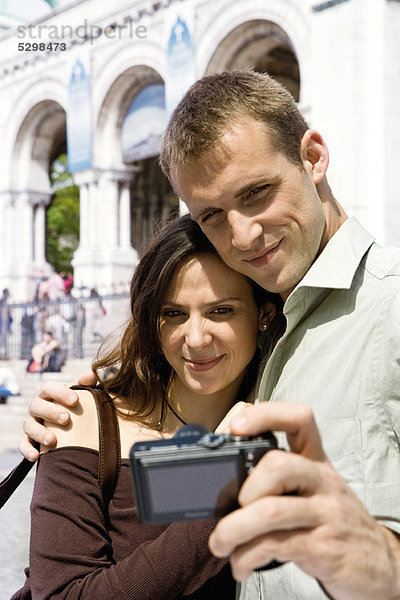 Mann fotografiert sich und seine Freundin mit Digitalkamera