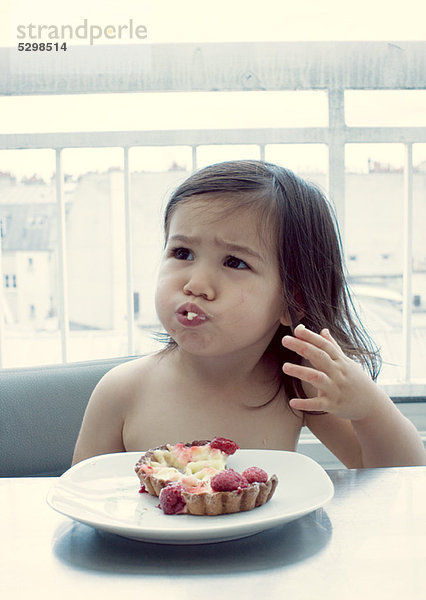 Kleines Mädchen mit Mund voller Essen