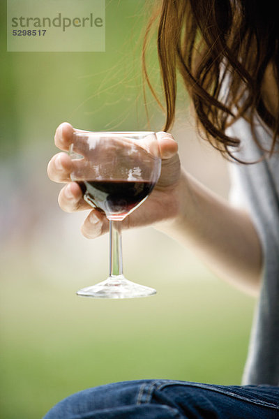 Frau hält ein Glas Rotwein  abgeschnitten