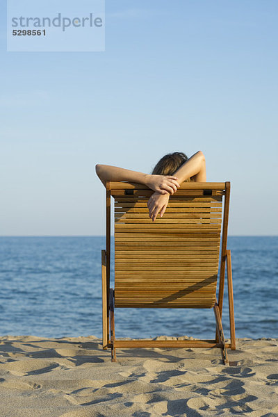 Frau entspannt sich im Liegestuhl am Strand