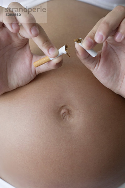 Schwangere Frau zerbricht Zigarette in zwei Hälften  abgeschnitten
