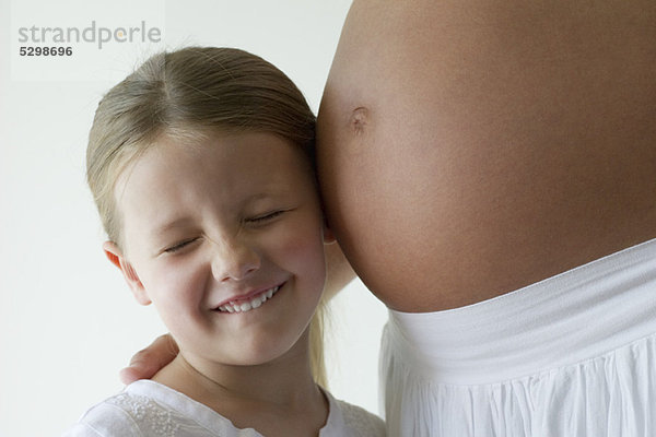 Mädchen hört auf Mutters schwangeren Bauch