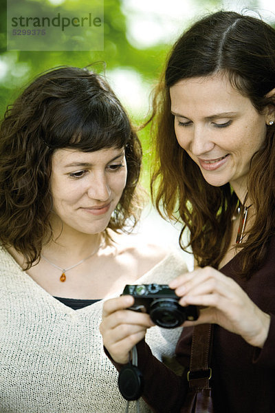 Frau zeigt Digitalkamera einem Freund