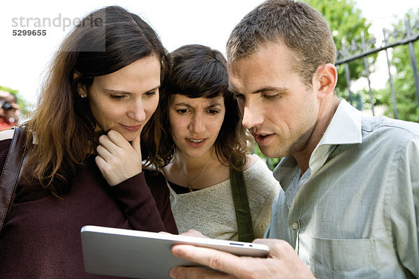 Freunde  die sich das digitale Tablett im Freien ansehen