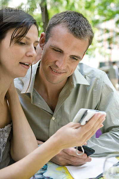 Ein Paar schaut sich das Handy zusammen im Freien an.
