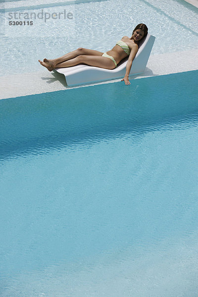 Junge Frau beim Sonnenbaden am Pool