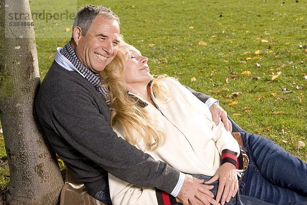 Fröhlicher reifer Mann umarmt Frau im Park
