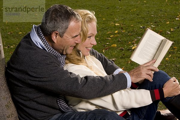 Reifes Paar im Freien liest ein Buch