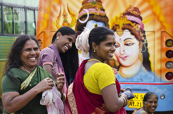 Pilgerinnen hinter einem bunt bemalten Bus vor dem Ramanathaswami-Tempel  sie lächeln und machen sich zurecht  Rameswaram  Tamil Nadu  Indien  Asien