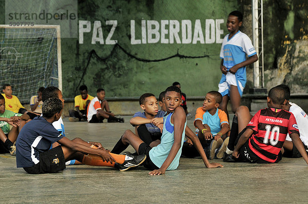 Jugendliche und Kinder auf einem Sportplatz vor einer Wand mit der Aufschrift  Paz Liberdade  Friede Freiheit  Armenviertel Favela Morro da Formiga  Stadtteil Tijuca  Rio de Janeiro  Brasilien  Südamerika
