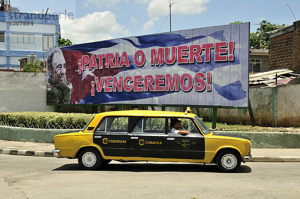 Stretch-Lada-Taxi vor politischer Propaganda  Fidel Castro  Socialismo o muerte  Sozialismus oder Tod  Bayamo  Kuba  Karibik
