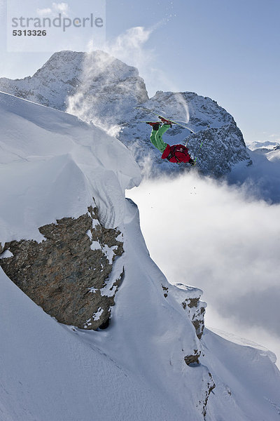 Freerider springt über Felsen im tiefverschneiten Gelände  Engadin  Schweiz  Europa