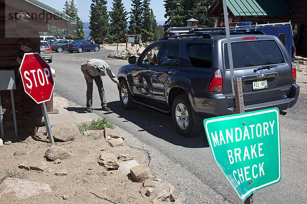 Ein Pikes Peak Highway-Ranger prüft die Temperatur der Bremsen an einem Auto  das den Pikes Peak Berg hinunter fährt  Colorado Springs  Colorado  USA