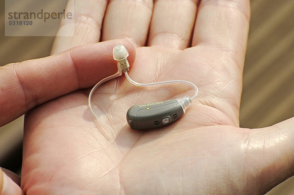 Modernes  kleines Hörgerät in der Hand einer Frau  Schwerhörigkeit