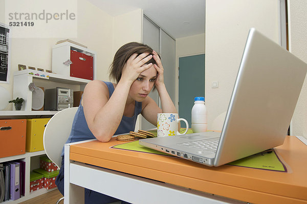 Junge Frau  Studentin in ihrer Wohnung  Arbeit am Laptop