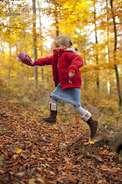 5 jähriges Mädchen springt vom Baumstumpf im Wald im Herbst
