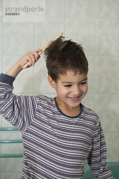 Junge  5 Jahre  bürstet sich die Haare im Badezimmer