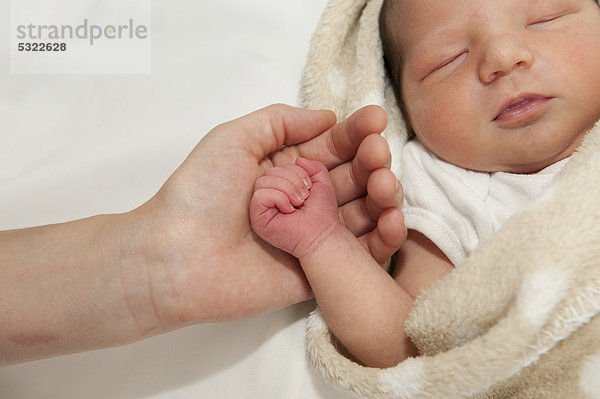 Hand der Mutter hält kleine Hand vom Neugeborenen