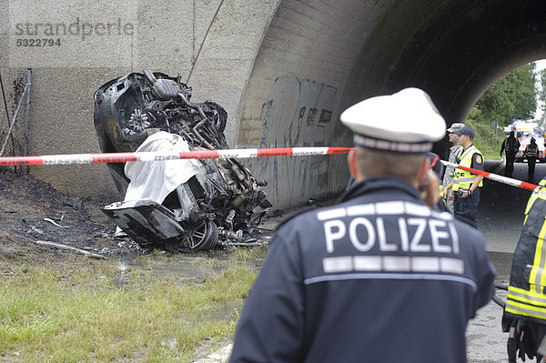 Das bis zur Unkenntlichkeit zerstörte und ausgebrannte Wrack eines Audi  nach heftigem Aufprall gegen einen Brückenbogen  Polizist im Vordergrund  Sindelfingen  Baden-Württemberg  Deutschland  Europa