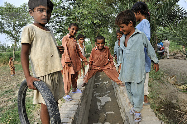Kinder spielen an einem Bewässerungskanal  Dorf Basti Lehar Walla  Punjab  Pakistan  Asien