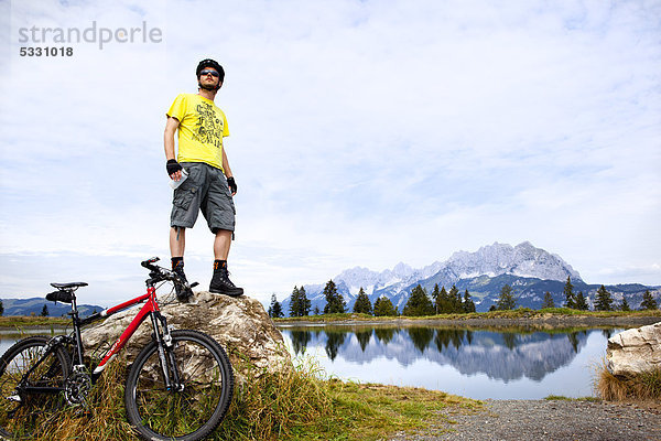 Mann mit Mountainbike auf einem Felsen schaut sich um