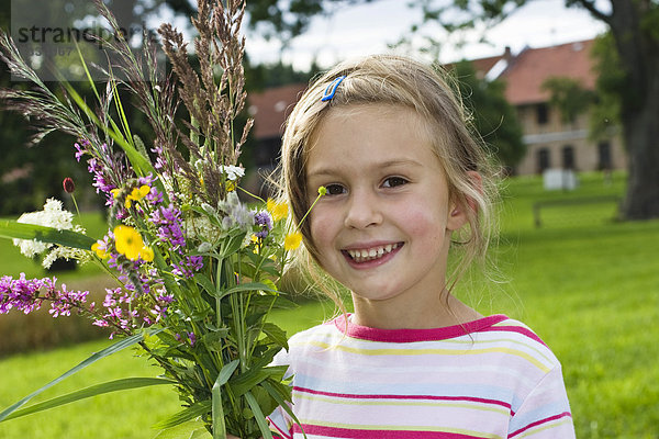Blondes Mädchen  6 Jahre  mit Blumenstrauß vor Bauernhof  Bayern  Deutschland  Europa