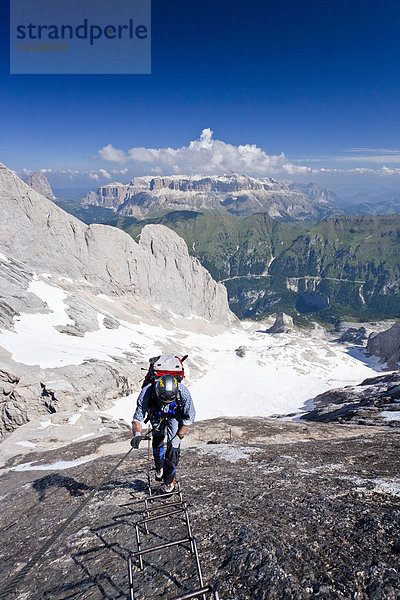 Bergsteiger beim Aufstieg zur Marmolata  Dolomiten  hinten der Sellastock sowie der Fedaiapass und der Fedaiasee  Klettersteig Westgrat  Trentino  Italien  Europa