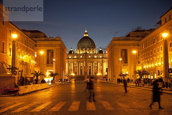 Fußgänger überqueren die Via della Conciliazione  Straße der Versöhnung  vor dem beleuchteten Petersdom in Rom  Italien  Europa