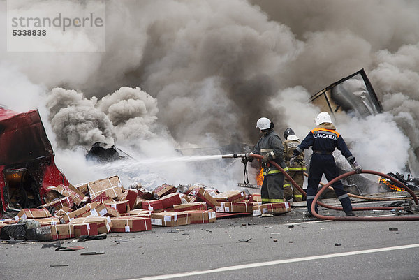 Feuerwehrmänner beim Löschen eines Feuers nach einem LKW-Verkehrsunfall auf der Bundesstraße zwischen Moskau und Sankt Petersburg  Nowgorod-Region  Russland  Europa