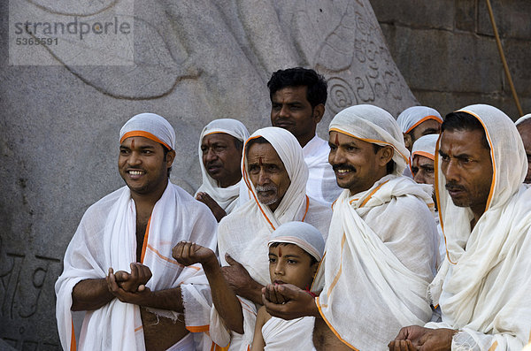 Gruppe von Jain-Pilgern beim Rezitieren religiöser Texte zu Füßen der Kolossalstatue von Gomateshwara  Sravanabelagola  Karnataka  Indien  Asien