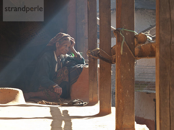 Alte Frau sitzt auf der Terrasse ihres Hauses  Chisapani  Helambu  Nepal  Asien