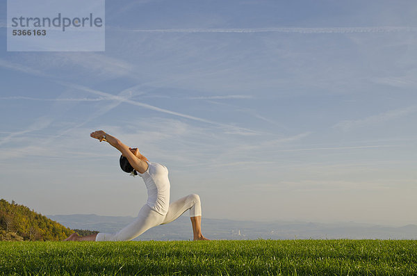 Junge Frau praktiziert Hatha-Yoga im Freien  zeigt die Stellung anjaneyasana  chandrasana  HalbmondStellung Nove Mesto  Okres Teplice  Tschechische Republik  Europa