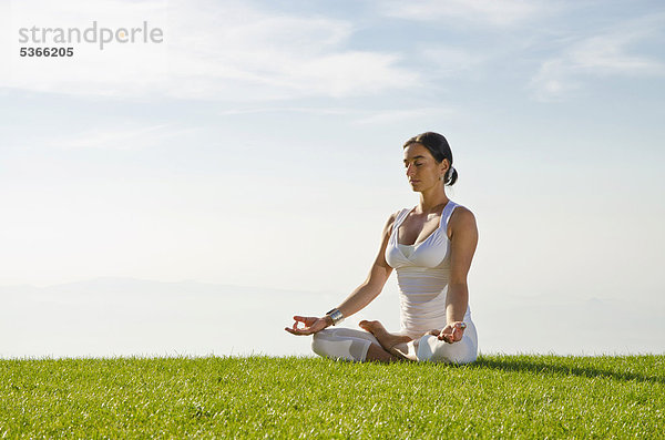 Junge Frau praktiziert Hatha-Yoga im Freien  zeigt die Stellung padmasana  Lotussitz  Nove Mesto  Okres Teplice  Tschechische Republik  Europa